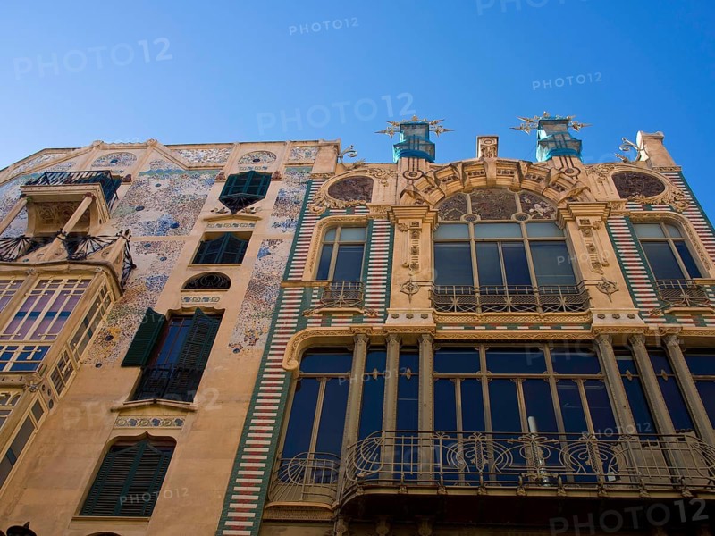 Decorative building with artistic mosaic work on the facade and several balconies under a clear sky, palma de Majorca with its historic houses, the great cathedral and flowers, palma, spain