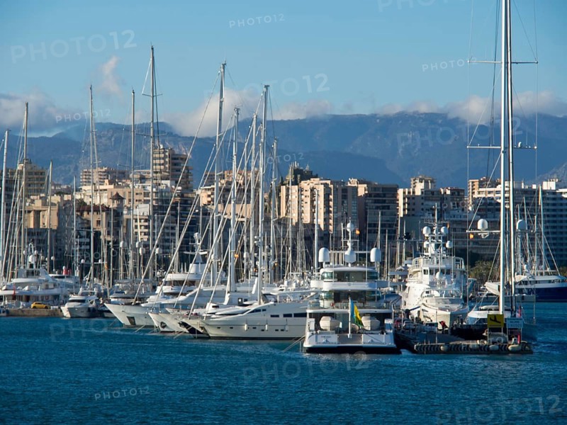 Marina with boats and skyscrapers against a mountain backdrop, palma de mallorca on the mediterranean sea with its historic houses, the great cathedral and flowers, palma, spain