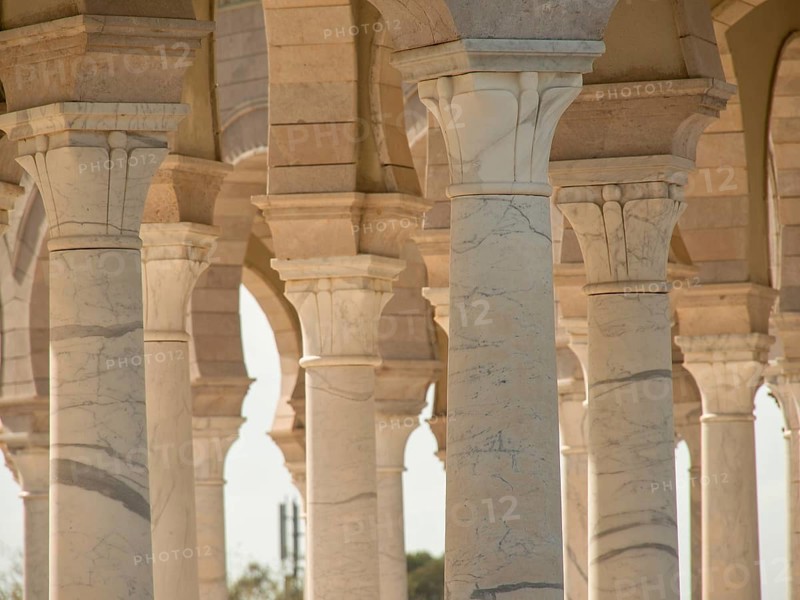 Several beige columns of an ancient arcade with shadow plays in the light, Tunis in Africa with ruins from Roman times, modern mosques and blue and white houses in sidi-bou-said, Tunis, Tunisia, Africa