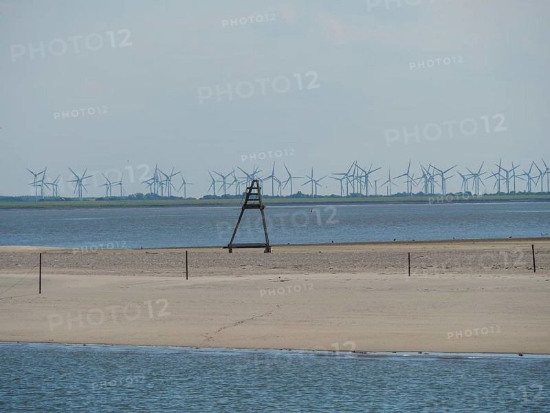 Sandy beach beach and the sea, in the background wind turbines under a slightly cloudy sky, Baltrum Germany