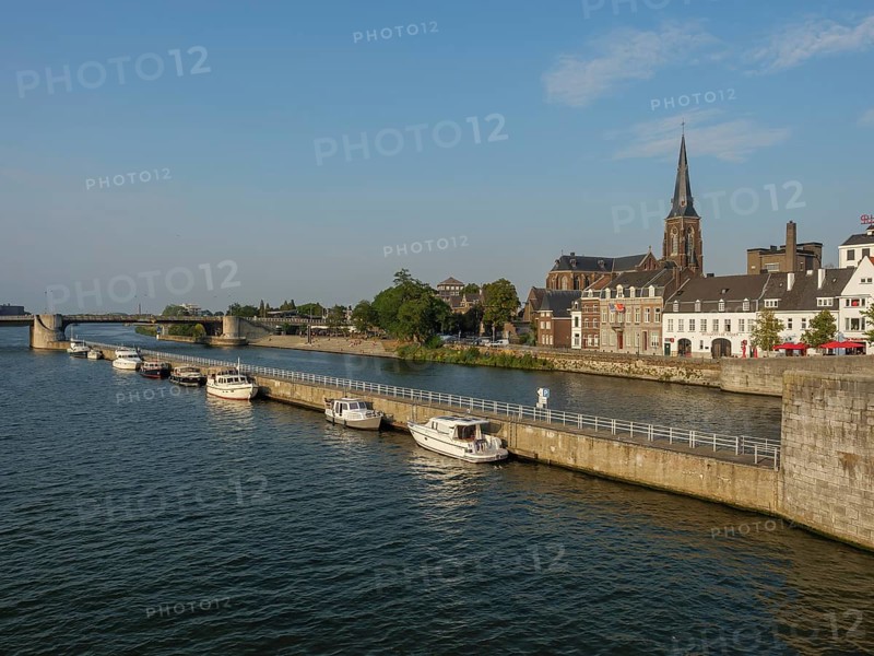 River view with neighbouring boats, historic buildings and a church, a bridge in the distance, Maastricht, Netherlands