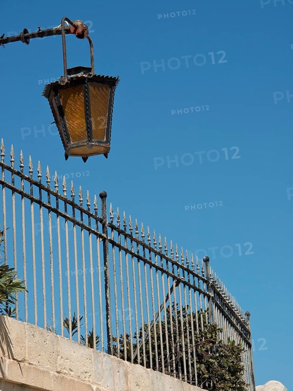 Street lamp over a metal fence with blue sky in the background, the town of mdina on the island of malta with historic houses, colourful balconies, magnificent churches, mdina, Malta, Europe