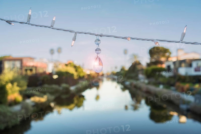 A string of lights and a quartz crystal are hanging on a string above a canal at Venice Beach, California