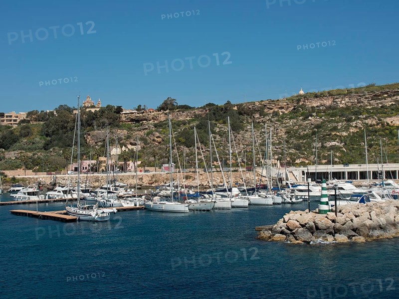 Marina with many sailing boats and adjacent hills under a bright blue sky, the island of Gozo with historic houses, colourful balconies, magnificent churches and boats in the harbour, Gozo, Malta, Europe