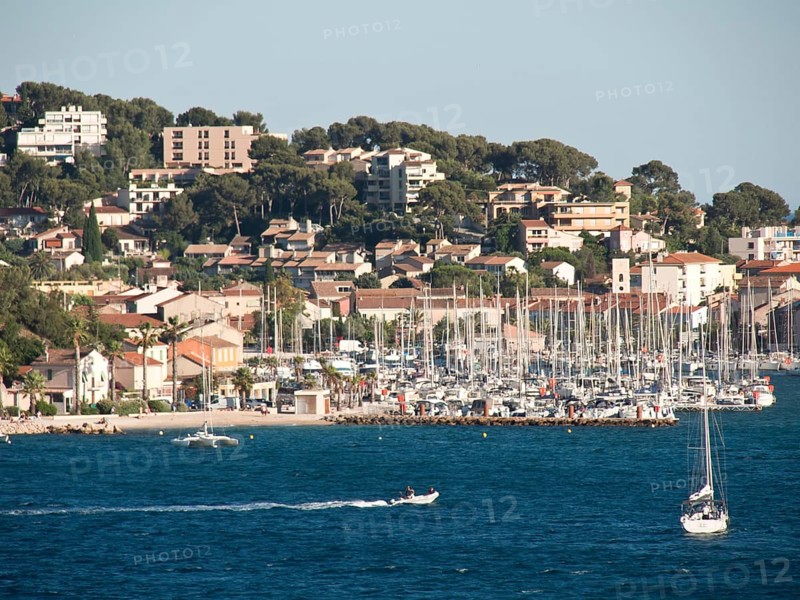 A coastal town with a marina full of boats, surrounded by houses and mountains, la seyne sur mer on the mediterranean sea with boats in the harbour, trees and houses on the coast, la seyne sur mer, france