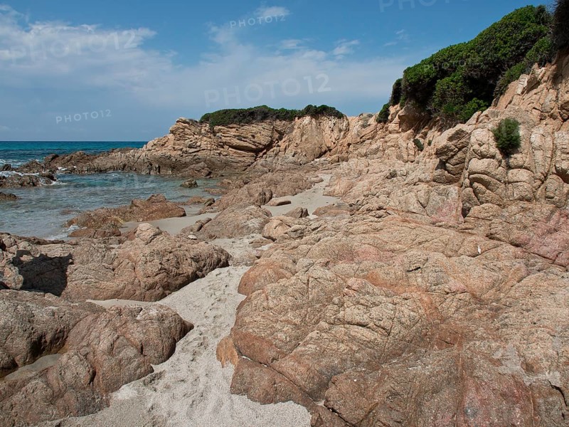 A rocky beach with sandy areas, surrounded by dense vegetation and clear blue sea, Corsica, Ajaccio, France, Europe