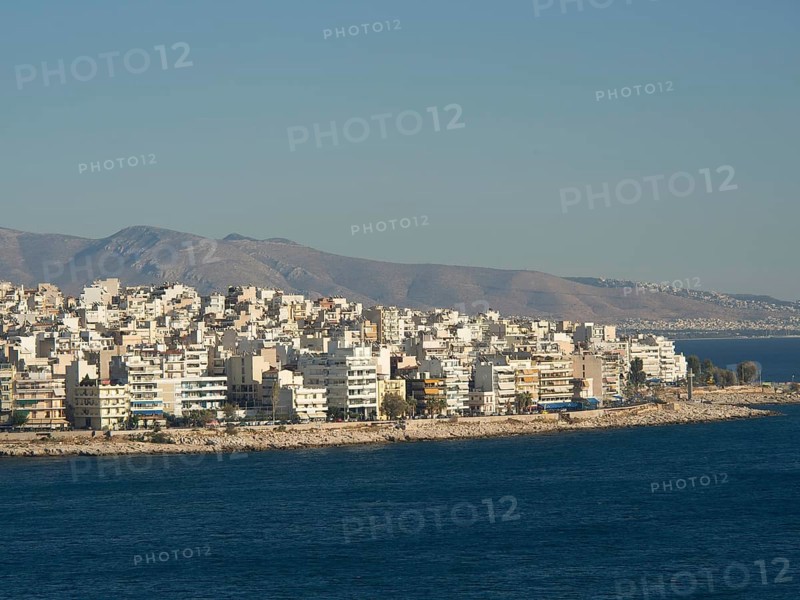 Coastal city skyline with many buildings bordering the blue sea and mountains in the background under a clear sky, Ancient buildings with columns and trees on the Acropolis in Athens against a blue sky, athens, greece