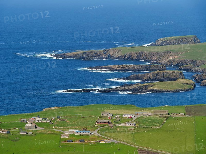 Coastal landscape with green fields, scattered houses and rocky cliffs by the deep blue sea, Green meadows by the sea with rocky shores and ruins, Lerwick, shetland