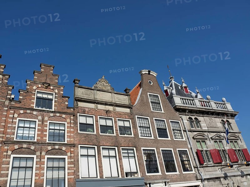 A row of historic buildings with striking facades under a bright blue sky, Haarlem, Netherlands