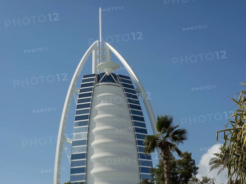 Close-up of the Burj Al Arab, a modern architectural icon, with some palm trees in the foreground and a clear sky, Dubai, Arab Emirates