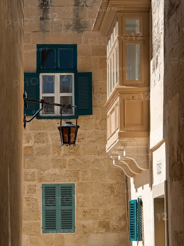 Narrow alley with old stone buildings, blue shutters and lanterns under the sun, the town of mdina on the island of malta with historic houses, colourful balconies, magnificent churches, mdina, Malta, Europe