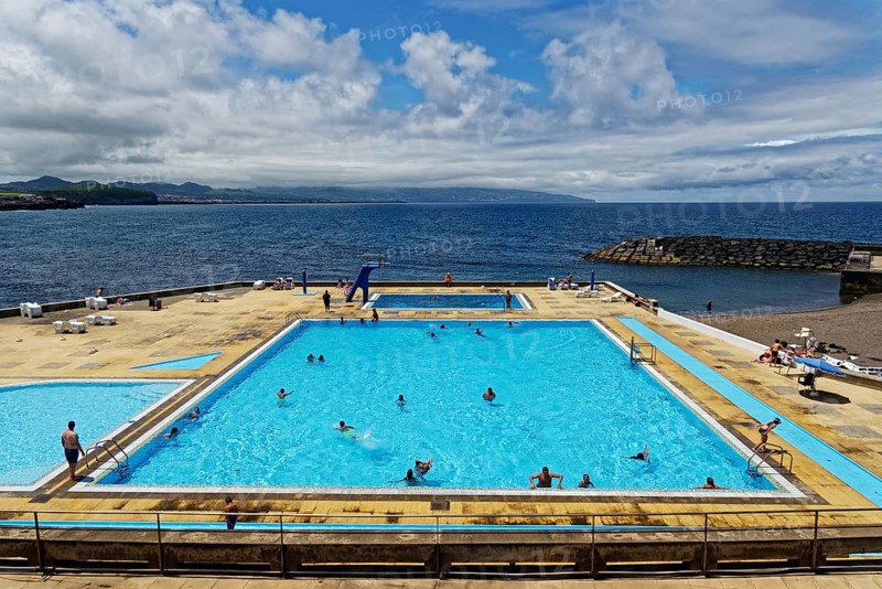 Large seawater swimming pool, filled with people, under a sunny, partly cloudy sky, coastal town of Ribeira Grande, Santa Barbara, Sao Miguel, Azores, Portugal, Europe