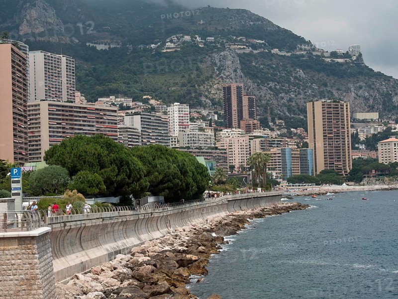 Coastline with promenade, skyscrapers and mountains behind, surrounded by sea and cloudy sky, monaco on the French Mediterranean coast, harbour in front of imposing city backdrop and historic buildings, Monte Carlo, Monaco, Europe