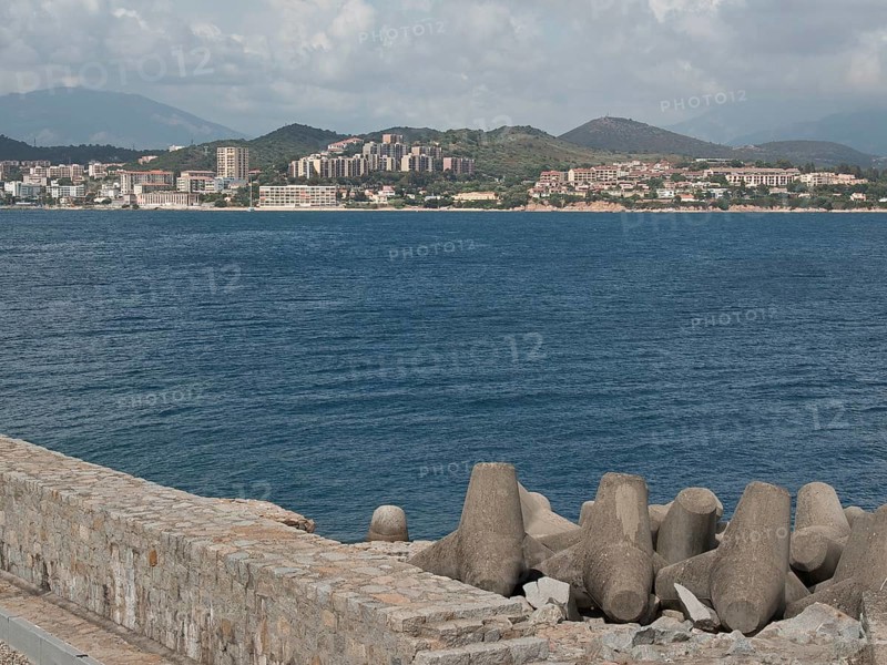 View of a coastal town across the sea, concrete breakwater in the foreground, Corsica, ajaccio, France, Europe