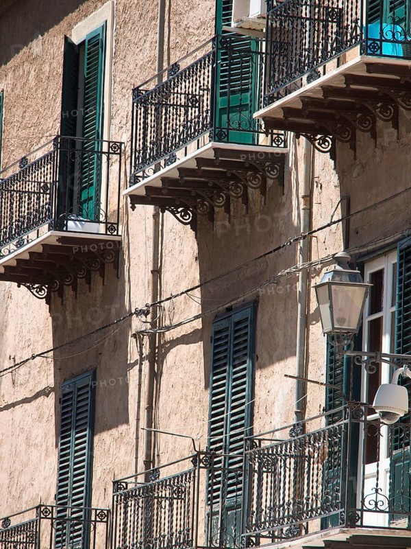 Buildings with green shutters and iron balconies, lanterns on the facade, shadow play on the wall, palermo in sicily with an impressive cathedral, monuments and old houses with balconies, palm trees and flowers in italy, palermo, sicily