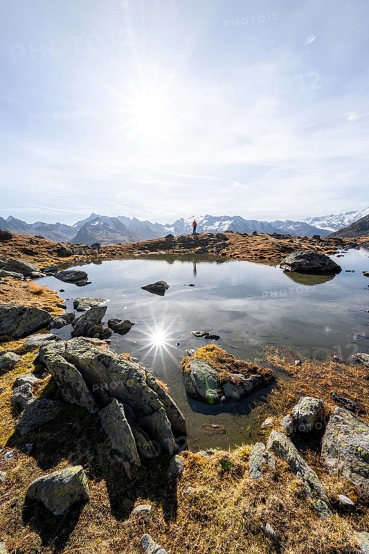 Mountaineers at a small lake on the high plateau of the Gurgler Seenplatte, glaciated mountain peaks in the background, in autumn, Sonnenstern, near Obergurgl, Oetztal Alps, Tyrol, Austria, Europe