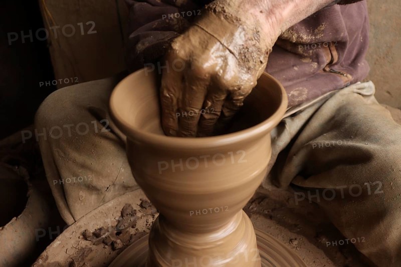 Hands molding clay on a pottery wheel, creating a vase, showcasing the art of crafting pottery