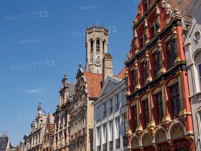 City scene with historic buildings with red facades and a bell tower under a clear blue sky, historic city by the river with ornate gables, old facades and historic towers, Bruges, Belgium, Europe