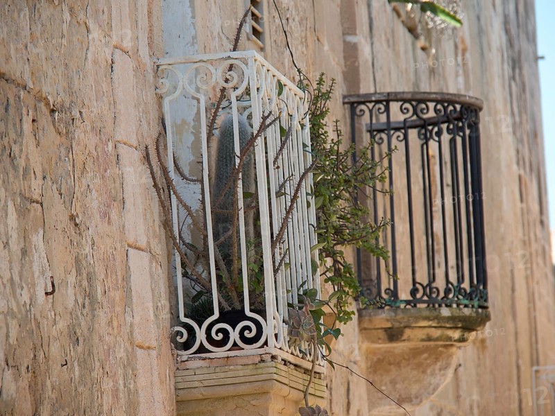 Old iron balconies and plants on a historic stone wall, the town of mdina on the island of malta with historic houses, colourful balconies, magnificent churches, mdina, Malta, Europe