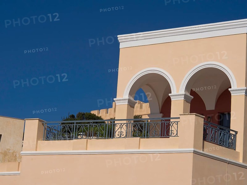 House with elegant arches and balcony in Mediterranean style under a blue sky, The volcanic island of Santorini with blue and white houses and churches, flowers and palm trees on a volcanic island, santorini, greece