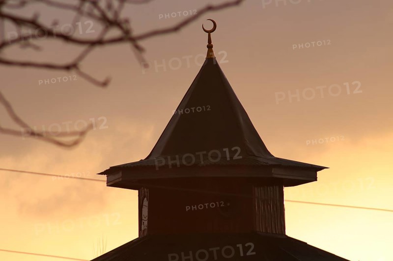 Silhouette of a mosque dome with a crescent at sunset