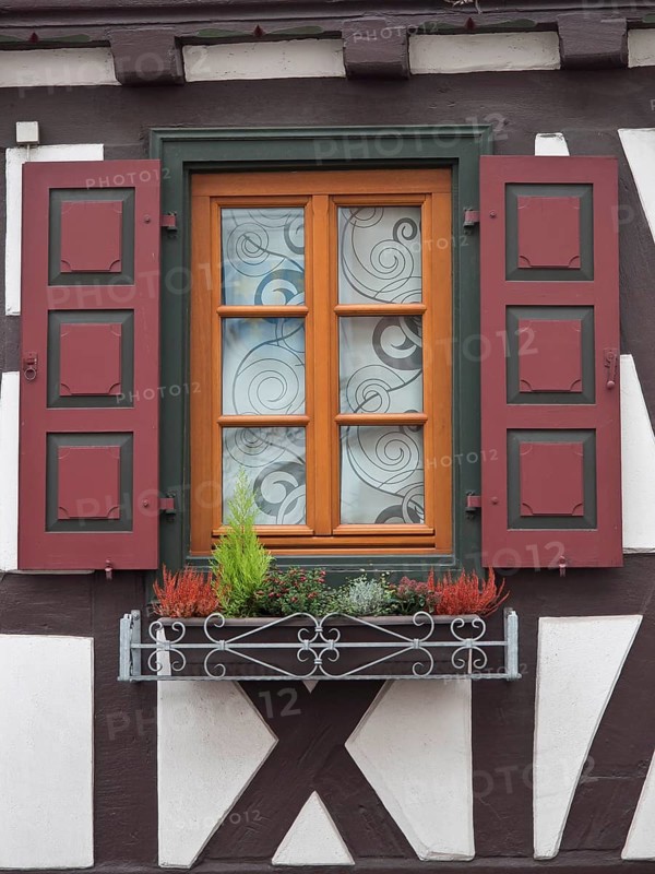 Close-up of a window with red shutters and decorative flower box of a half-timbered house, kandel, germany