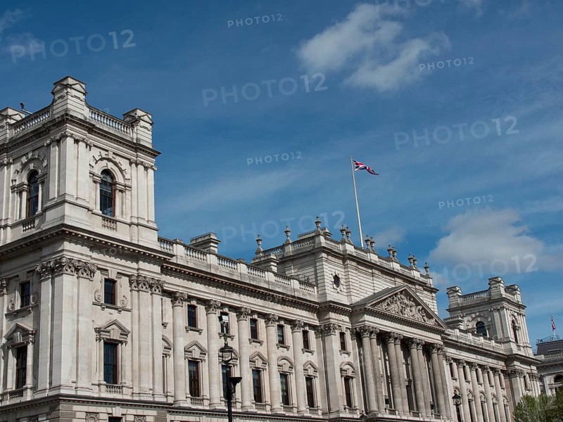 Large historic building with a waving Union Jack flag on the roof, against a cloudy sky, London, England, United Kingdom, Europe
