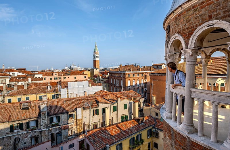 Young man looking over Venice with campanile, tower of Palazzo Contarini del Bovolo, palace with spiral staircase, Venice, Veneto, Italy, Europe