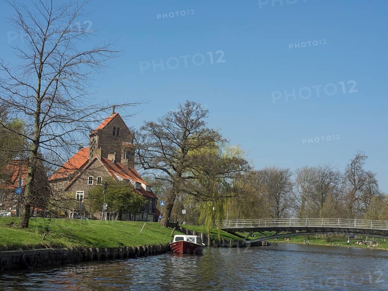 Landscape with a riverside church, a picturesque bridge and a boat on the water, Haarlem, Netherlands