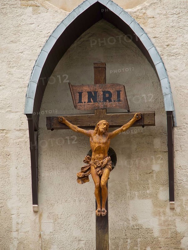 Wooden cross with Jesus sculpture and INRI sign on a church wall, Marseille on the Mediterranean Sea with the old cathedral and ships in the historic harbour, rocky coast on the Mediterranean Sea, marseille, france