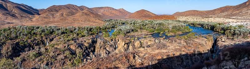 Panorama, Kunene River with green vegetation in dry red mountain landscape, waterfall and African Baobab (Adansonia digitata), in the evening light, Epupa Falls, Kunene, Namibia, Africa