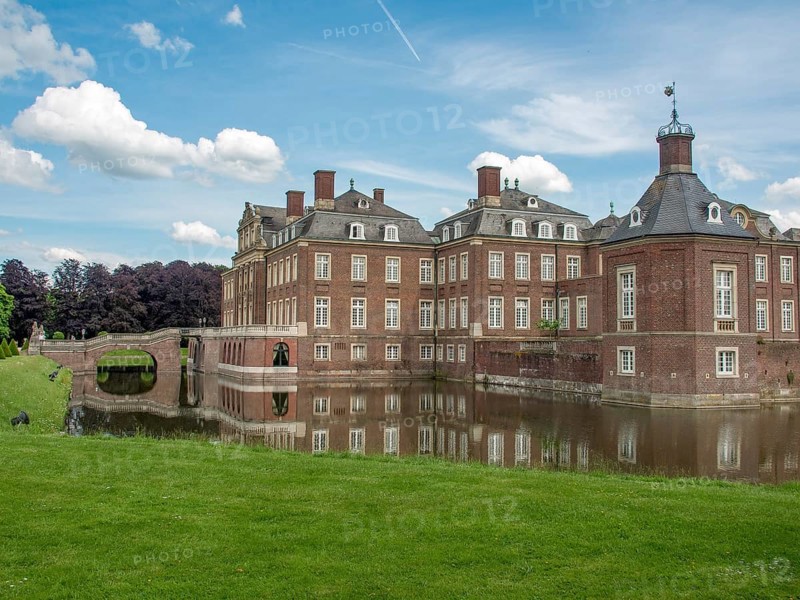 Historic castle with moat and reflection in the water, surrounded by lawn and blue sky with clouds, historic castle with a green park with sculptures and paths, nordkirchen, germany