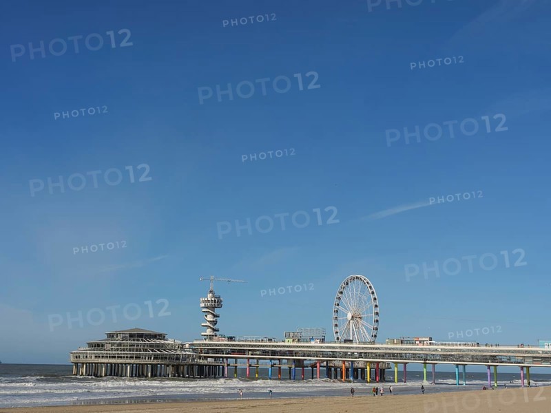 Pier with Ferris wheel and tower on the beach, sea in the background under a blue sky, parasols and a pier on the beach of Scheveningen, Scheveningen, Netherlands