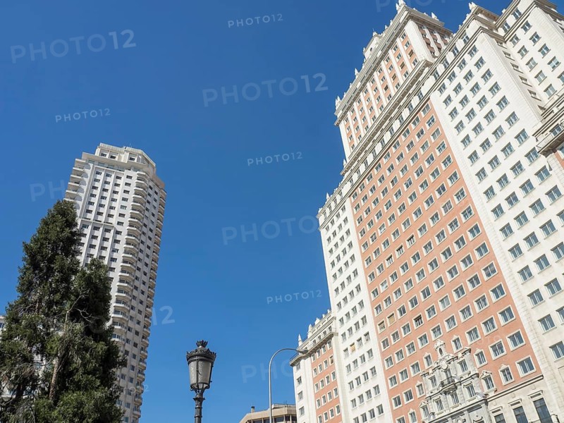 Two tall, modern buildings under a clear blue sky, a street lamp and a tree in the foreground, Madrid, Spain, Europe