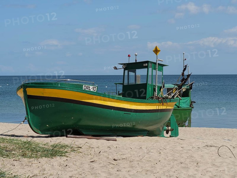 Two green and yellow fishing boats standing near the sea on a sandy beach, green and yellow fishing boats on the beach in Poland, sopot, poland