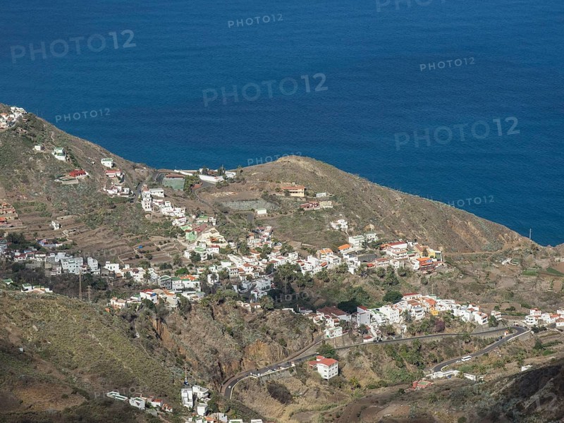 Panorama of a coastal village with houses on rolling hills and the ocean in the background, the canary island of tenerife with rugged mountains, small mountain villages and beautiful lava beaches, tenerife, spain