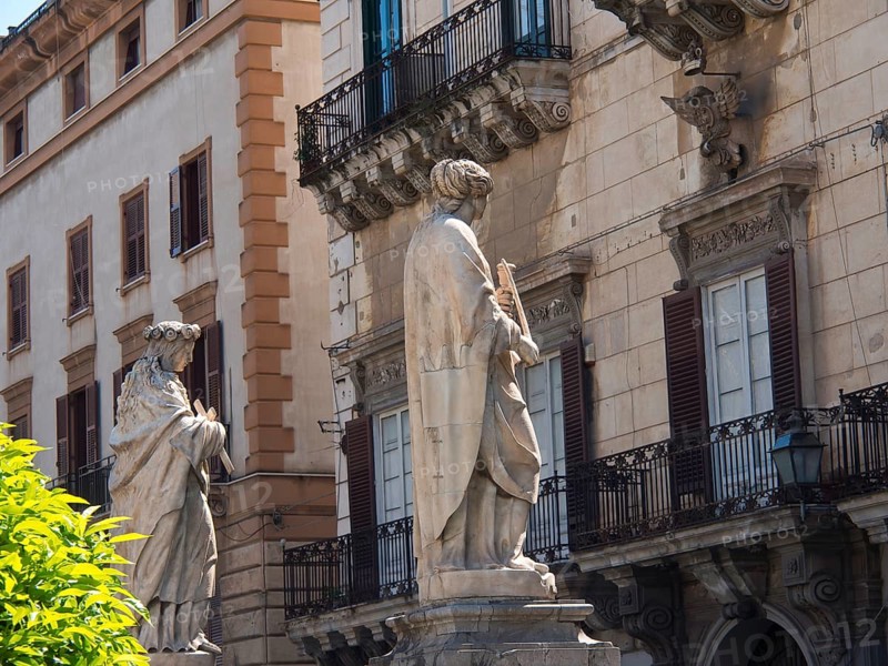 Historic buildings with balustrades and sculptures in the city, palermo in sicily with an impressive cathedral, monuments and old houses with balconies, palm trees and flowers in italy, palermo, sicily