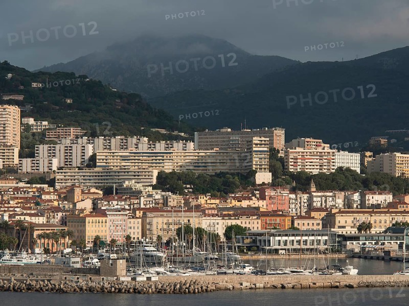 Coastal town with harbour in front of a mountain backdrop under a cloudy sky, Corsica, ajaccio, France, Europe