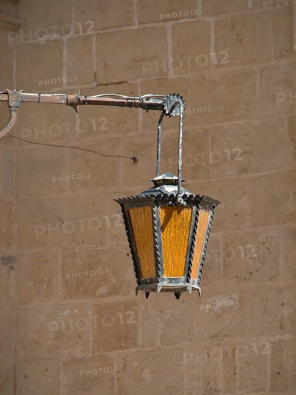 Antique metal and glass lantern, suspended from a sturdy stone wall, gives a rustic ambience, the town of mdina on the island of malta with historic houses, colourful balconies, magnificent churches, mdina, Malta, Europe