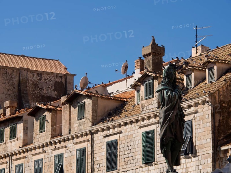 Statue in front of old buildings with tiled roofs and several satellite dishes, the old town of Dubrovnik with historic houses, churches, red roofs and fortress walls, dubrovnik, coratia