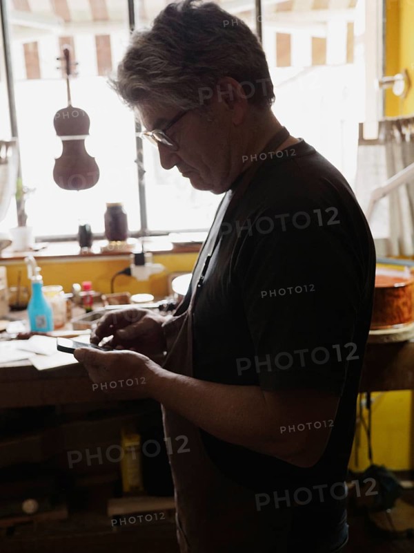 Craftsman focused on work in a sunlit workshop with various tools and instruments