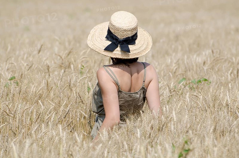 Woman with a Straw Hat Standing in a Wheat Field in a Sunny Summer Day in Ticino, Switzerland, Europe