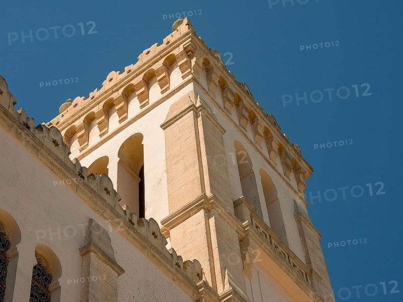 A beige tower rises into the clear blue sky, the weather is sunny, Tunis in Africa with ruins from Roman times, modern mosques and blue and white houses in sidi-bou-said, Tunis, Tunisia, Africa