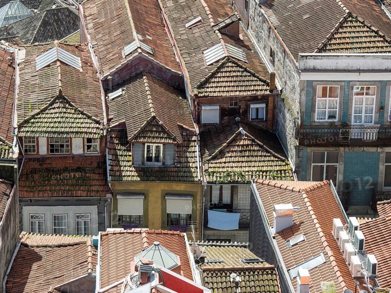View of a cluster of red tiled roofs of the old town, conveying a bustling and authentic urban atmosphere, old town with historic houses and red roofs in poertugal, porto, portugal