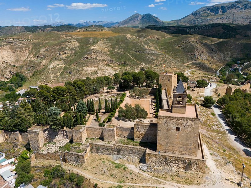 Aerial view of a historic fortress, surrounded by trees and mountains, with impressive walls and towers, from above by vegetation in sunny weather, fortress hill, Alcazaba, Antequera, Malaga, Andalusia, Spain, Europe