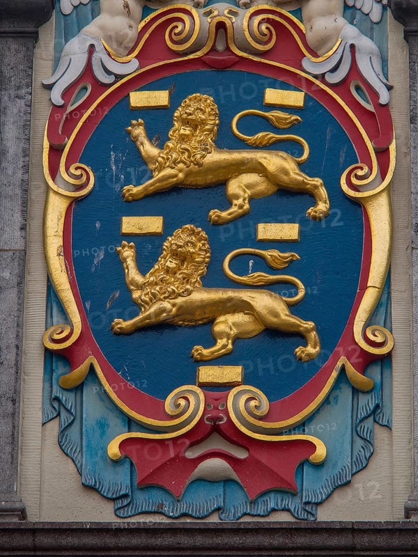 Close-up of a coat of arms with golden lions and colourful decorations, historic houses in Hoorn and ships in the harbour, hoorn, the netherlands