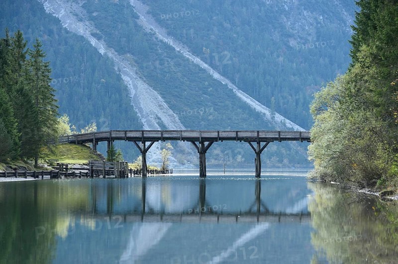 Landscape of a bridge over a small part of a clear lake (Plansee) in autumn in Tirol