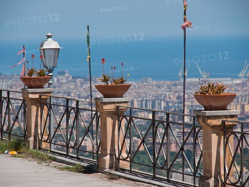Urban view of the sea with pots and plants on the railing, clear sky and summer feeling, palermo in sicily with an impressive cathedral, monuments and old houses with balconies, palm trees and flowers in italy, palermo, sicily