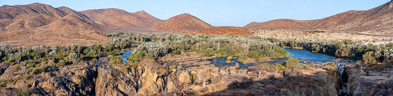 Panorama, Kunene River with green vegetation in dry red mountain landscape, waterfall and African Baobab (Adansonia digitata), in the evening light, Epupa Falls, Kunene, Namibia, Africa