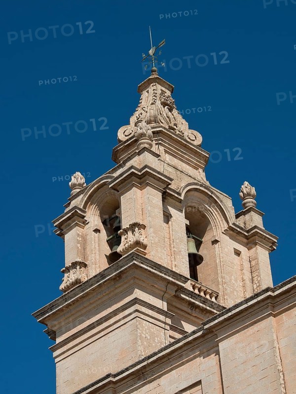 A large stone church tower with architectural details rising into the blue sky, the town of mdina on the island of malta with historic houses, colourful balconies, magnificent churches, mdina, Malta, Europe